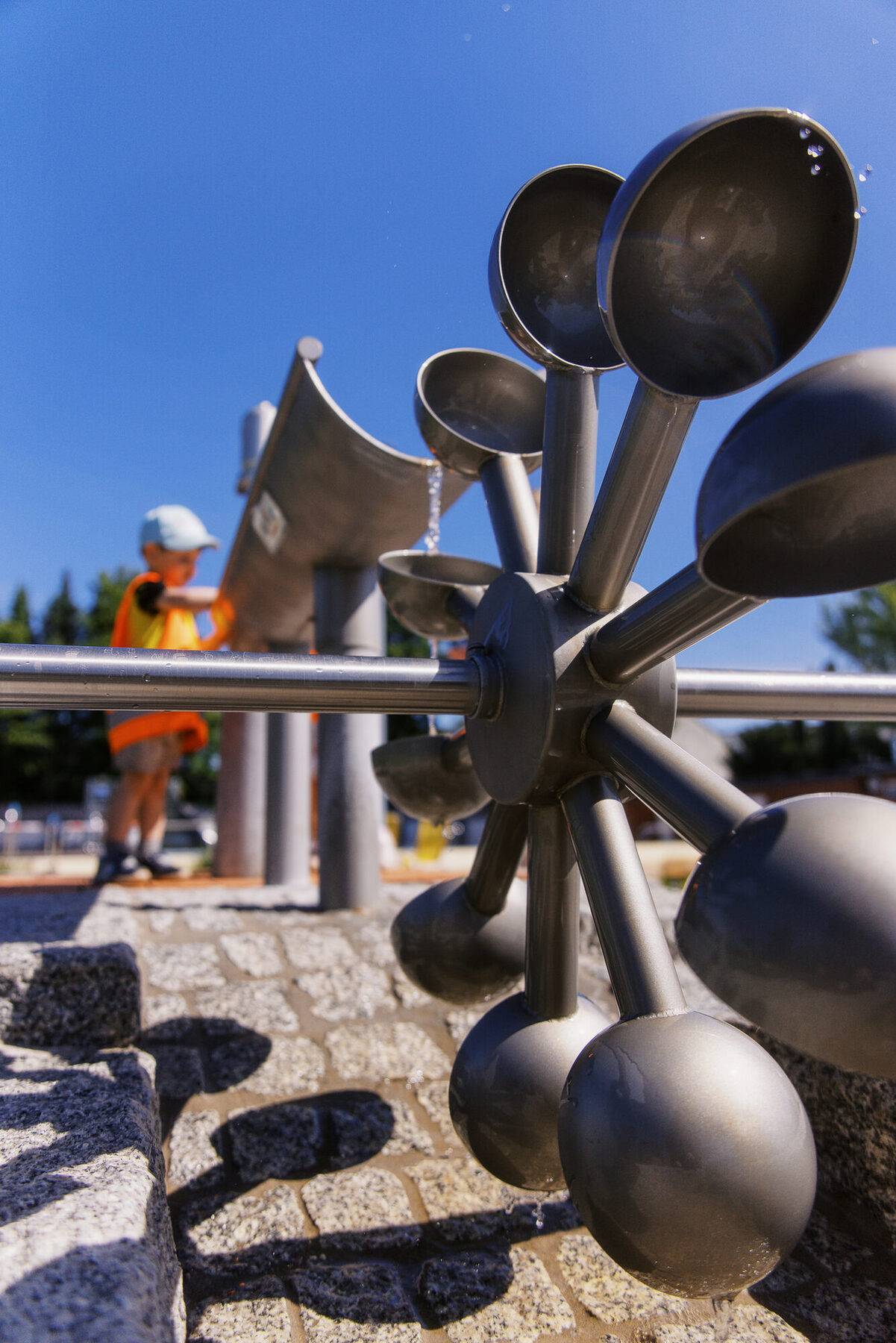 Metallene Klangtrichter stehen auf einem Spielplatz vor blauem Himmel