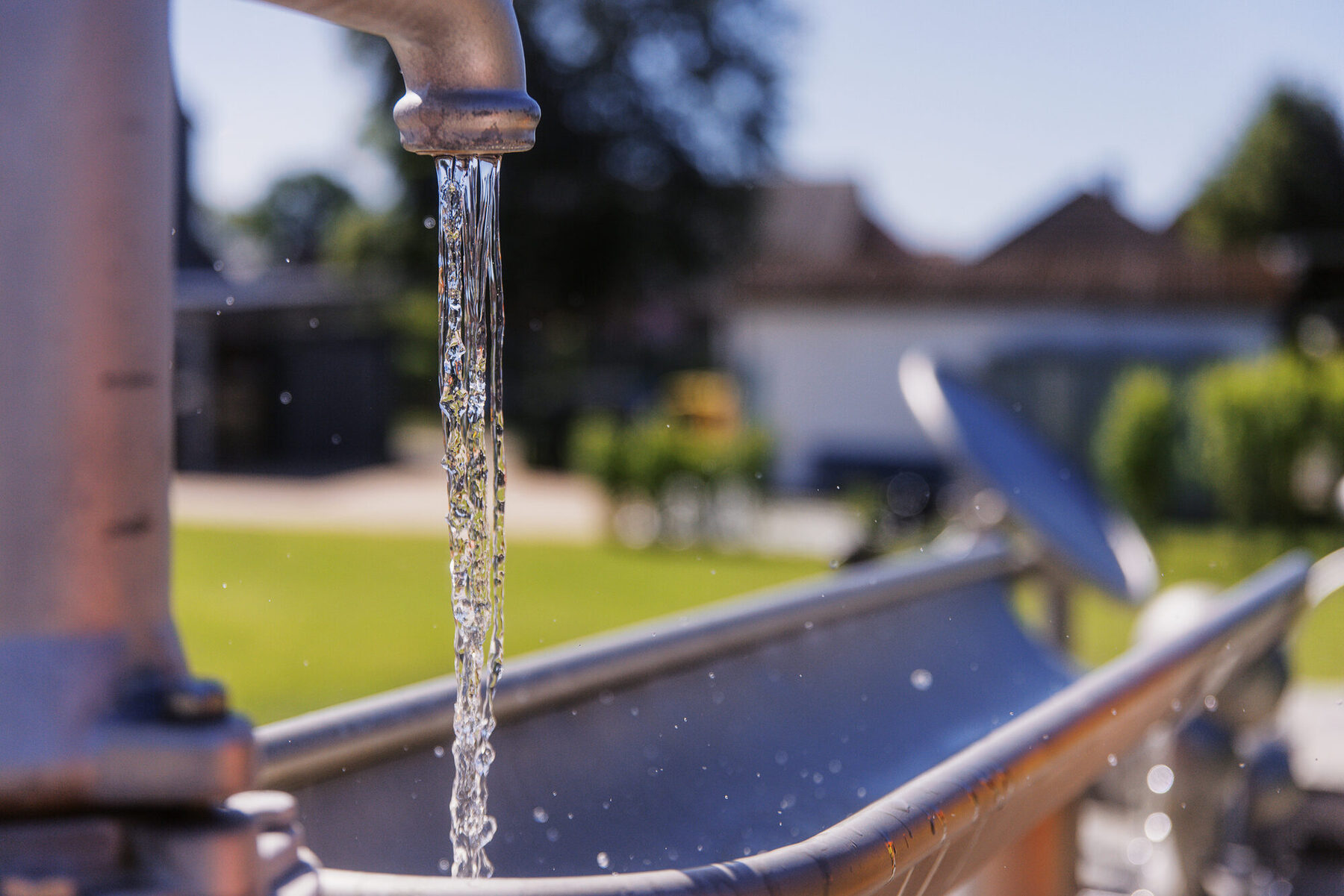 Wasser läuft aus einer Metallpumpe in eine Spielrinne