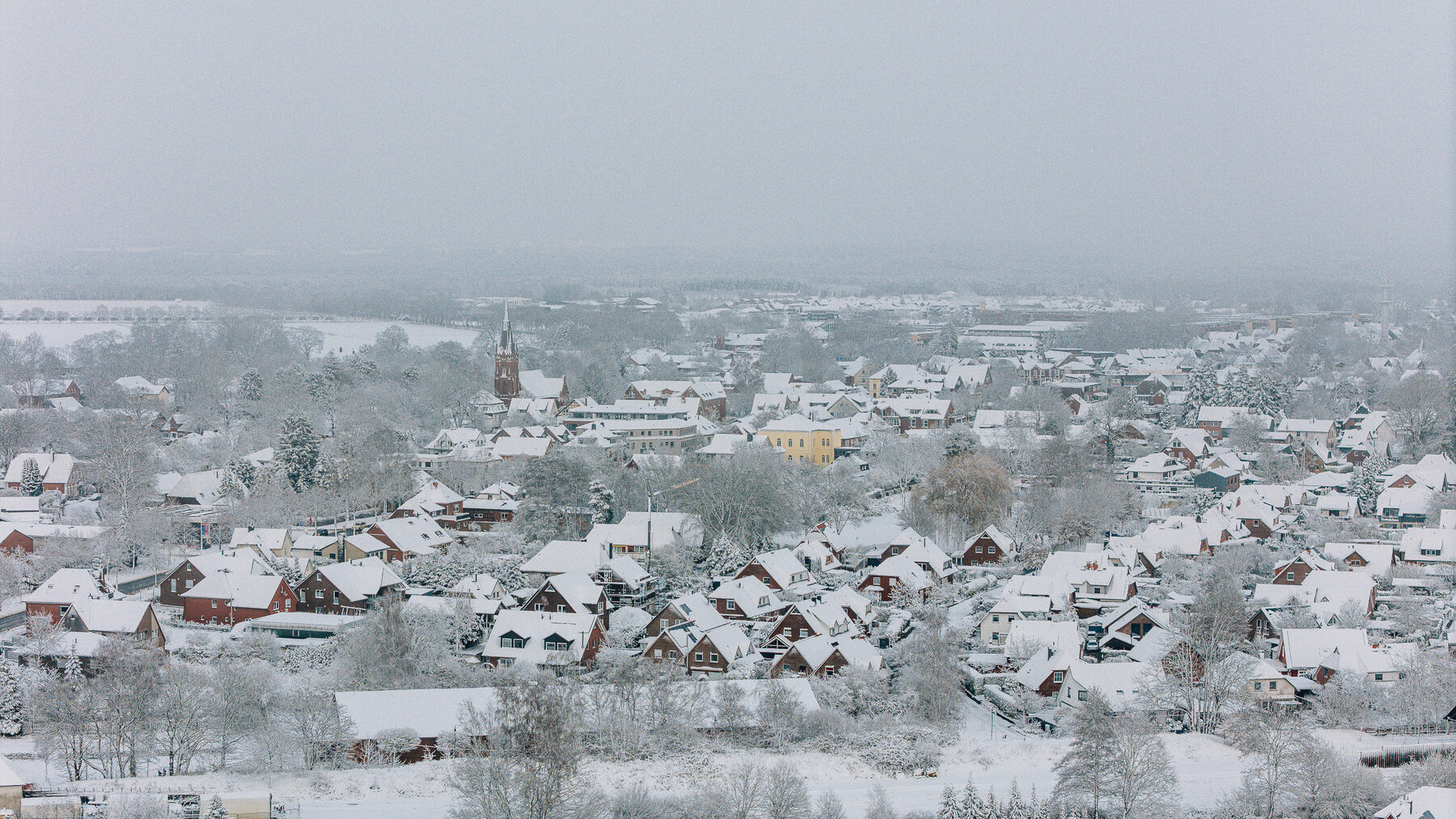 Winterliches Tostedt mit verschneiten Dächern aus der Luft